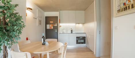 Una cocina moderna con armarios blancos, una mesa de comedor con sillas y una planta en maceta.