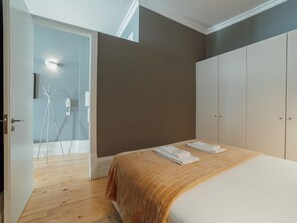 Ein Schlafzimmer mit einem Bett, einem Kleiderschrank und einer Tür zu einem anderen Raum.