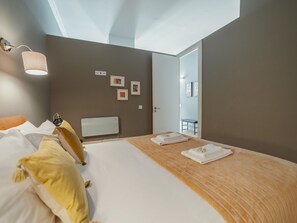 A modern bedroom with a bed, bedside table, lamp, and artwork on the wall. - Apartment  by Interhome (Porto)