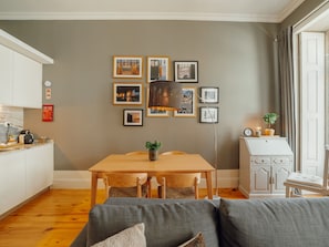 A modern kitchen with white cabinetry, a dining table with chairs, and a grey sofa. - Apartment  by Interhome (Porto)