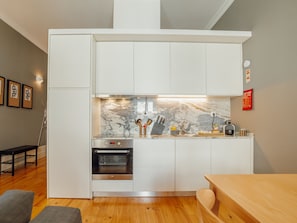 A modern kitchen with white cabinetry, a built-in oven, and a marble backsplash. - Apartment  by Interhome (Porto)