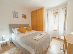 Ein Hotelzimmer mit einem Bett, einem Nachttisch, einem Schreibtisch und einem Kleiderschrank.