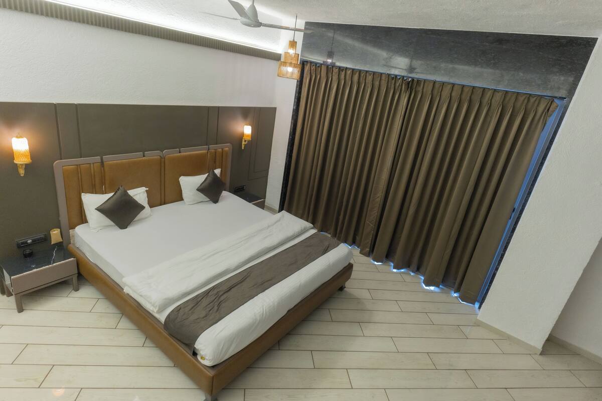 A modern hotel room with a large bed, bedside lamps, a nightstand, and a ceiling fan.