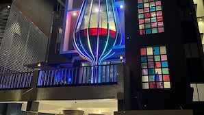 Un edificio moderno con una fachada de vidrio singular y una estructura iluminada destacada en el centro.