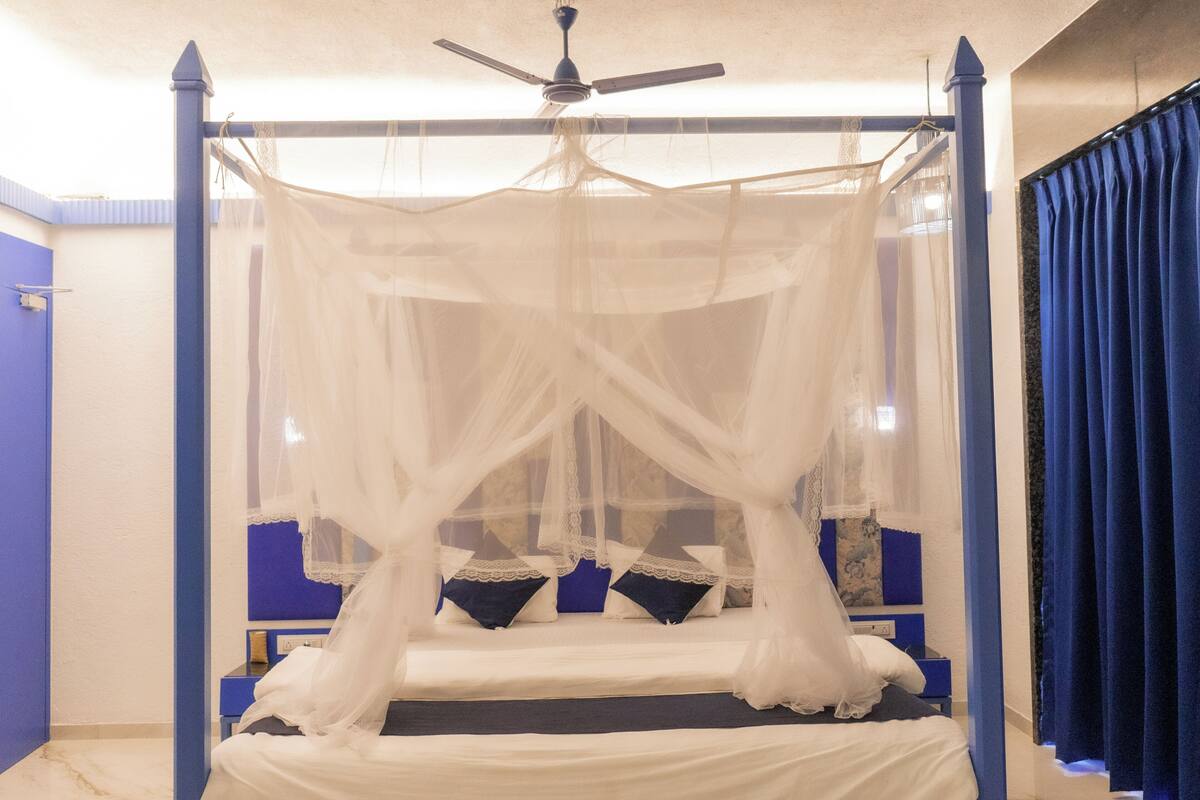 A four-poster bed with a canopy, a ceiling fan, and a blue accent wall.