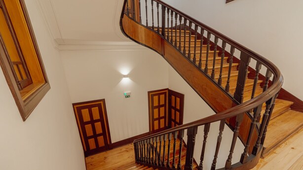 En spiralformet trappe med trætrin og balustre, der fører op til en platform med en lampe.