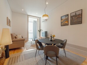 En moderne stue med sofa, spisebord med stole, fjernsyn og kunst på væggen.