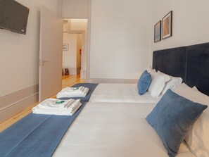 A hotel room with two beds, a dark headboard, and a door leading to a hallway. - Apartment  by Interhome (Porto)