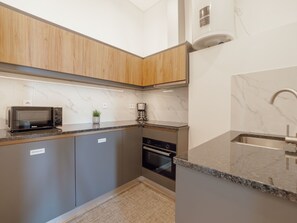 A modern kitchen with a built-in microwave, coffee maker, and oven. - Apartment  by Interhome (Porto)