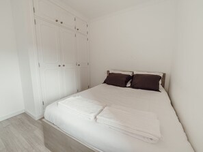Une chambre à coucher avec un lit, des rideaux blancs et un plancher en bois.