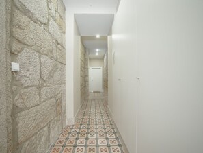 A narrow hallway with stone walls, a tiled floor, and a white door at the end. - Apartment  by Interhome (Porto)