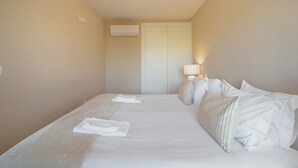 Habitació d'hotel amb llit, almoines, làmpada de nit i aparell d'aire condicionat.