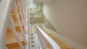 Una escala de fusta amb baranes blanques que mena a una paret de pedra.