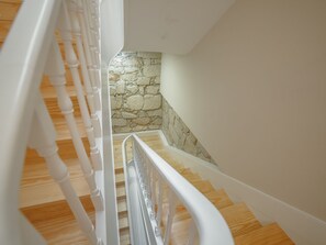 A wooden staircase with white railings leading to a stone wall. - Apartment  by Interhome (Porto)