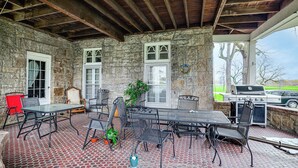 A covered patio with stone walls, a grill, and outdoor seating. - Historic Victorian Cottage, 1 Mi to Niagara Falls (Niagara Falls)