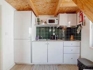 A compact kitchen with white cabinets, a microwave, and a small countertop area. - Apartment  by Interhome (Porto)