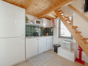 Une cuisine moderne avec des meubles blancs, un pare-feu vert et un plafond en bois.