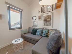 Ein modernes Wohnzimmer mit einer Eckcouch, einer runden Uhr und gerahmten Bildern an der Wand.