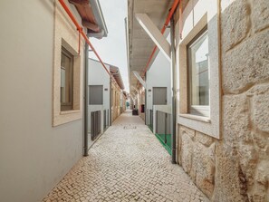 A corridor with tiled flooring, white walls, and windows with metal grilles. - Apartment  by Interhome (Porto)