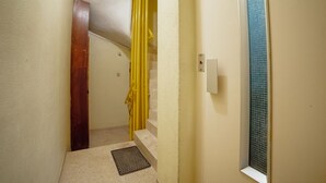 A narrow hallway with a wooden door, a yellow curtain, and a window with a textured glass pane. - Apartment  by Interhome (Porto)