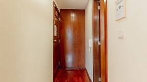 A hallway with wooden flooring, a closed door, and a welcome sign with Wi-Fi symbol. - Apartment  by Interhome (Porto)