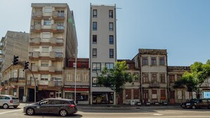 A multi-story building with balconies, a street view, and a car in the foreground. - Apartment  by Interhome (Porto)