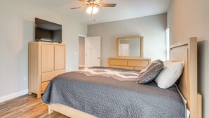 Una camera da letto con un letto, una ventola a soffitto, un armadio, uno specchio e una porta.