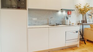 Eine moderne Küche mit weißen Schränken, einer eingebauten Mikrowelle, einer Edelstahl-Spüle und einem Geschirrspüler.