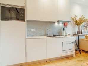 Eine moderne Küche mit weißen Schränken, einer eingebauten Mikrowelle, einer Edelstahl-Spüle und einem Geschirrspüler.