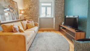 Ein Wohnzimmer mit Steinwand, einer Couch, einem Fernseher und einem Fenster.