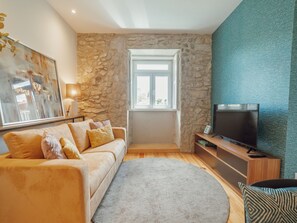Ein Wohnzimmer mit Steinwand, einer Couch, einem Fernseher und einem Fenster.