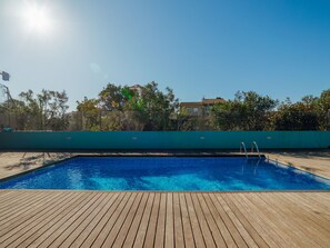 A swimming pool with a wooden deck, surrounded by a fence and trees. - Apartment  by Interhome (Porto)