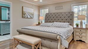 Ein Schlafzimmer mit einem großen Bett, einer Bank, einem Nachttisch, einem Deckenventilator und einem Fenster.