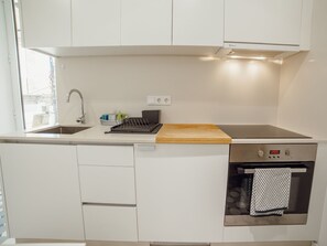 A compact kitchen with a built-in oven, a sink, and a wooden cutting board. - Apartment  by Interhome (Porto)
