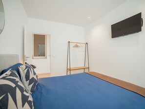 A bedroom with a bed, a wardrobe, a mirror, and a television. - Apartment  by Interhome (Porto)