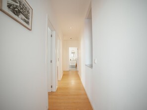 A hallway with a wooden floor leading to a bathroom with a sink and mirror. - Apartment  by Interhome (Porto)