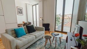 Uma sala de estar moderna com um sofá, uma mesa redonda pequena e uma poltrona.