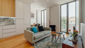 Uma sala de estar moderna com um sofá, uma mesa de centro e vista para a cidade por grandes janelas.