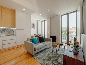 Ein modernes Wohnzimmer mit einer Couch, einem Couchtisch und Blick auf die Stadt durch große Fenster.