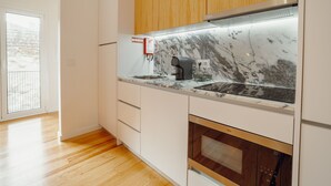 Una cucina moderna con mobili bianchi, un piano di lavoro in marmo e forno a incasso.
