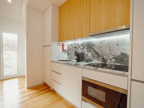 Eine moderne Küche mit weißen Schränken, einer Marmorarbeitsplatte und einem eingebauten Backofen.