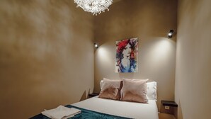 A bedroom with a bed, pillows, a blanket, a painting on the wall, and a light fixture. - Apartment  by Interhome (Porto)