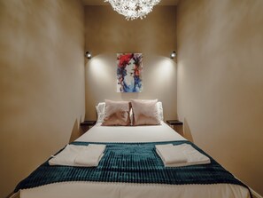 A hotel room with a large bed, two bedside tables, a wall-mounted painting, and a chandelier. - Apartment  by Interhome (Porto)