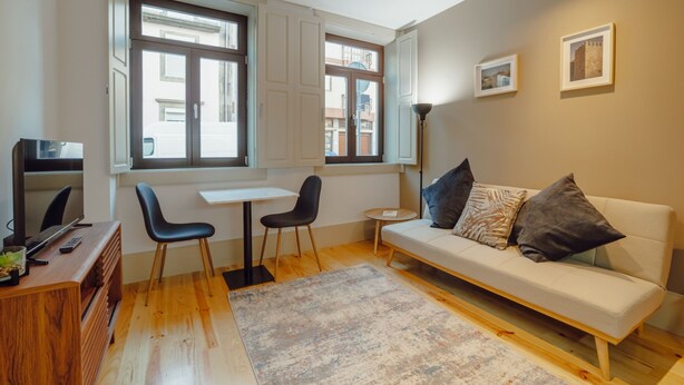 A modern living room with a sofa, two chairs, a small table, and a TV. - Apartment  by Interhome (Porto)