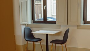 A small dining area with a table and two chairs, a window with a view, and a patterned rug on the floor. - Apartment  by Interhome (Porto)