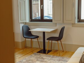 A small dining area with a table and two chairs, a window with a view, and a patterned rug on the floor. - Apartment  by Interhome (Porto)
