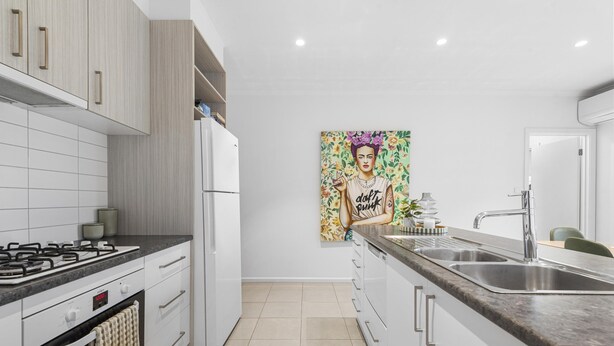 A modern kitchen with white cabinets, a stainless steel sink, and a painting on the wall. - 55 Seconds of Summer by Ready Set Stay (Rosebud)