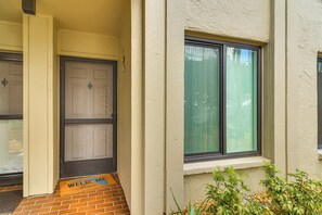 Ein Gebäudeeingang mit Fußmatte, einer Tür und einem Fenster mit Rollläden.