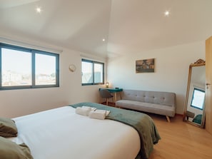 Ein Hotelzimmer mit einem großen Bett, einer Couch, einem Schreibtisch und einem Spiegel.