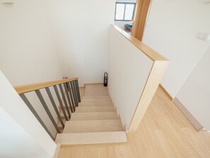 Eine Treppe mit Holzbodenstufen und Metallgeländern, die zu einer Zwischenebene mit einem Fenster führt.